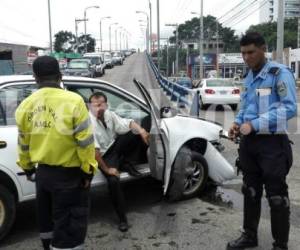 Taxista ebrio se lleva de encuentro a motocilista y se estrella en puente de Comayagüela. Policías lo capturaron y lo esposaron a la puerta de su vehículo.