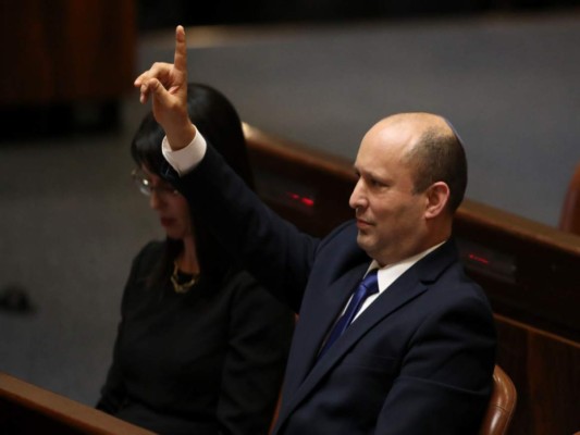 El nuevo primer ministro de Israel, Naftali Bennett, levanta la mano durante una sesión del Knésset, el domingo 13 de junio de 2021, en Jerusalén. (AP Foto/Ariel Schalit).