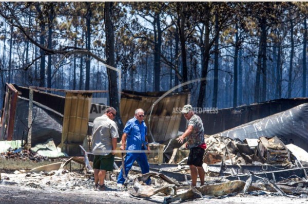 En esta fotografía de archivo del 25 de junio de 2018, residentes rescatan sus pertenencias de sus casas quemadas en Eastpoint, Florida.