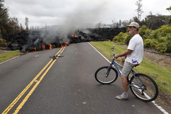 En esta fotografía de archivo del 5 de mayo de 2018, Sam Knox, habitante de Leilani Estates, observa una franja de lava que cruza un camino en Pahoa, Hawai.