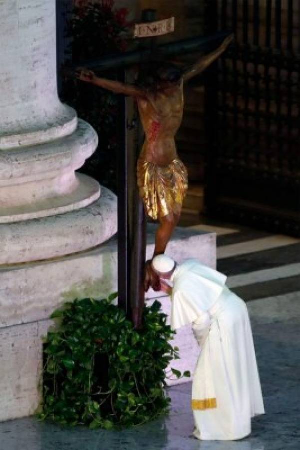 Pope Francis kisses a miraculous crucifix that in 1552 was carried in a procession around Rome to stop the great plague, that was brought from the San Marcello al Corso church in Rome, during a moment of prayer on the sagrato of St Peters Basilica, the platform at the top of the steps immediately in front of the façade of the Church, to be concluded with the Pope giving the Urbi et Orbi Blessing, on March 27, 2020 at the Vatican. (Photo by YARA NARDI / POOL / AFP)