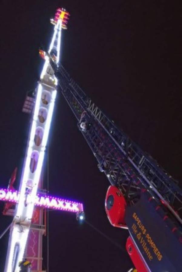 TOPSHOT - Fire brigade personnel conduct rescue operations after eight people got stuck high in the air on a giant funfair ride in the Brittany city of Rennes late on December 31, 2018. - It was only supposed to last a few minutes for a thrill on New Year's Eve, but eight French people ended up spending the night stuck high up in the air after a technical incident caused the ride to break down. (Photo by Antoine AGASSE / AFP)