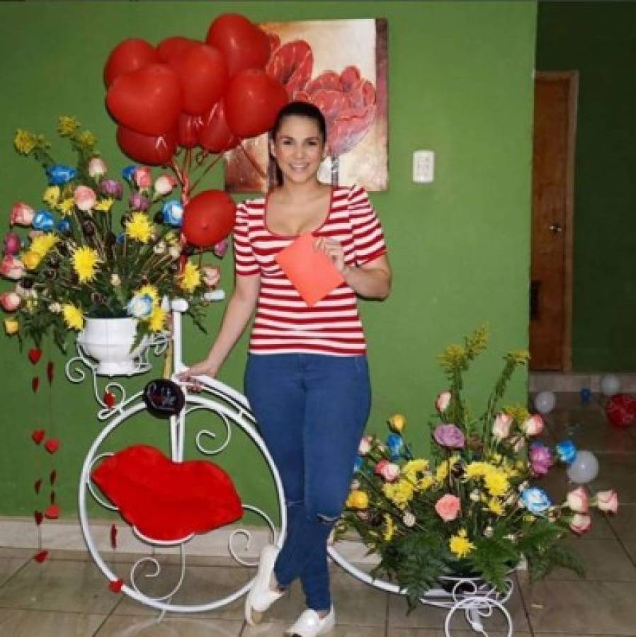 Stefany Galeano posa con una enorme bicicleta de jardín repleta de rosas coloridas.