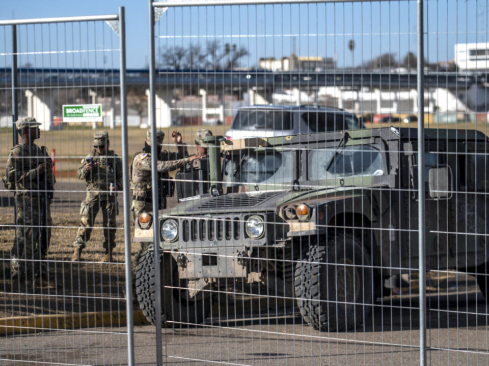 Miembros de la Guardia Nacional de Texas vigilan detrás de una cerca en Shelby Park el 3 de febrero de 2024 en Eagle Pass, Texas .