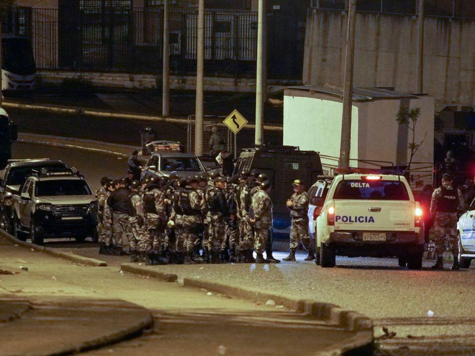 Oficiales de la Policía Nacional hacen guardia afuera de la prisión de Turi mientras los funcionarios penitenciarios que estaban siendo rehenes por los reclusos son liberados, en Cuenca, Ecuador, a última hora del 13 de enero de 2024.