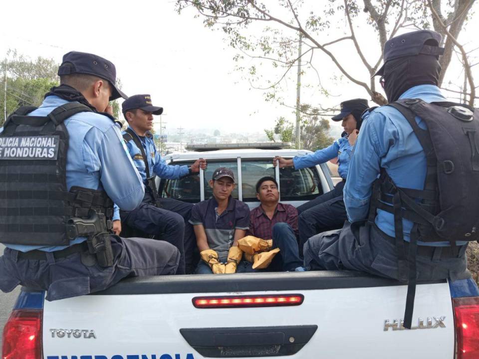 Dos de los detenidos cuando eran trasladados con sus manos cubiertas para proteger la evidencia que pudiera haber en sus manos tras el crimen múltiple.