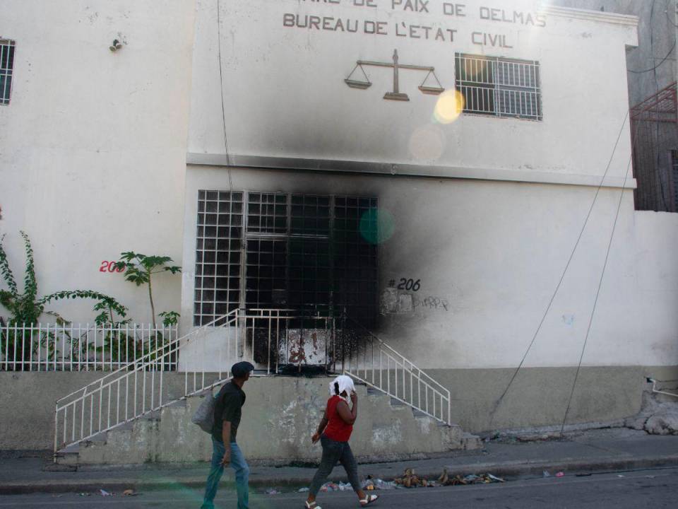 La gente pasa y mira el tribunal incendiado el día anterior por bandas armadas, en Puerto Príncipe, Haití, el 6 de marzo de 2024.