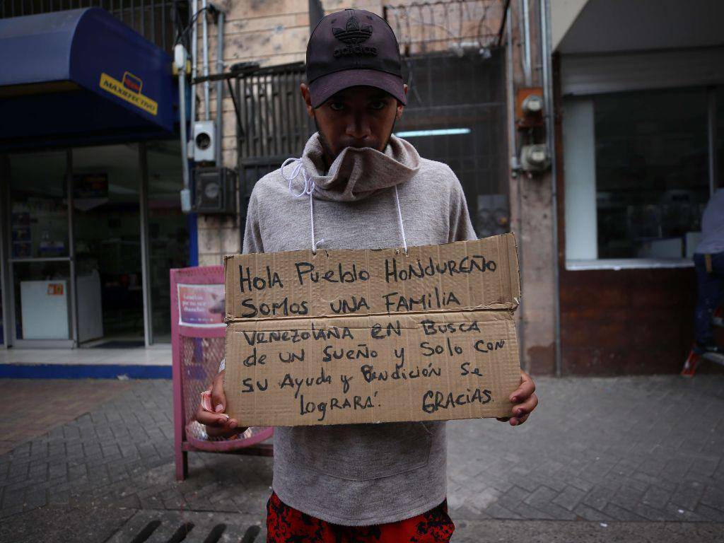 $!Un joven venezolano con un cartel en el cuello pedía dinero en Comayagüela. Los migrantes piden durante uno, dos o tres días para ajustar el pasaje del bus que los lleva hasta Copán.