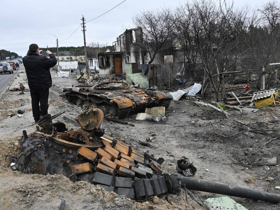 Un hombre toma una foto de los restos de un tanque junto a las casas residenciales destruidas en el pueblo de Zalissya, al noreste de Kiev.