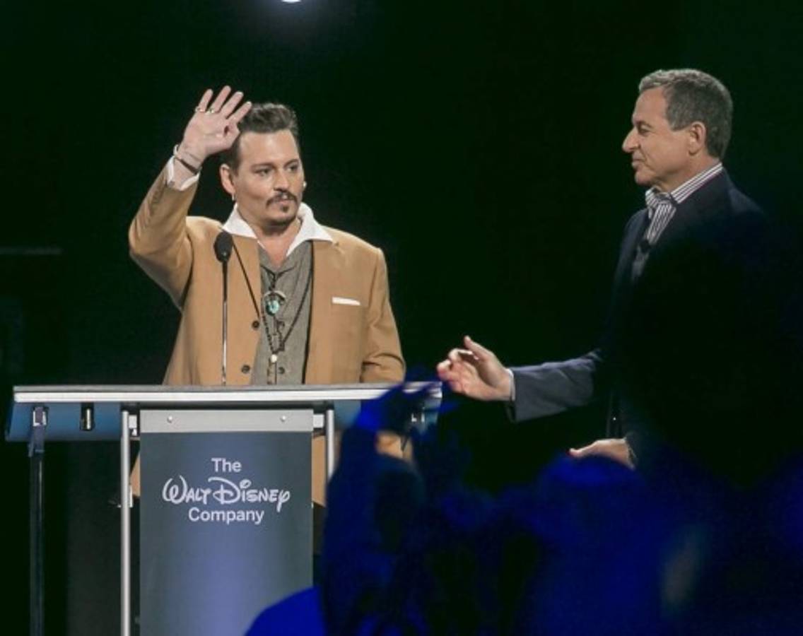 Actor Johnny Depp, left, makes a surprise appearance at Disney's D23 Expo, a fan convention, to accept the Disney Legend Award honor from Disney CEO Bob Iger on Friday, Aug. 14, 2015, in Anaheim, Calif. Depp has starred in Disney's 'Pirates of the Caribbean' series as Captain Jack Sparrow as well as their live-action 'Alice in Wonderland' as the Mad Hatter. (AP Photo/Damian Dovarganes)