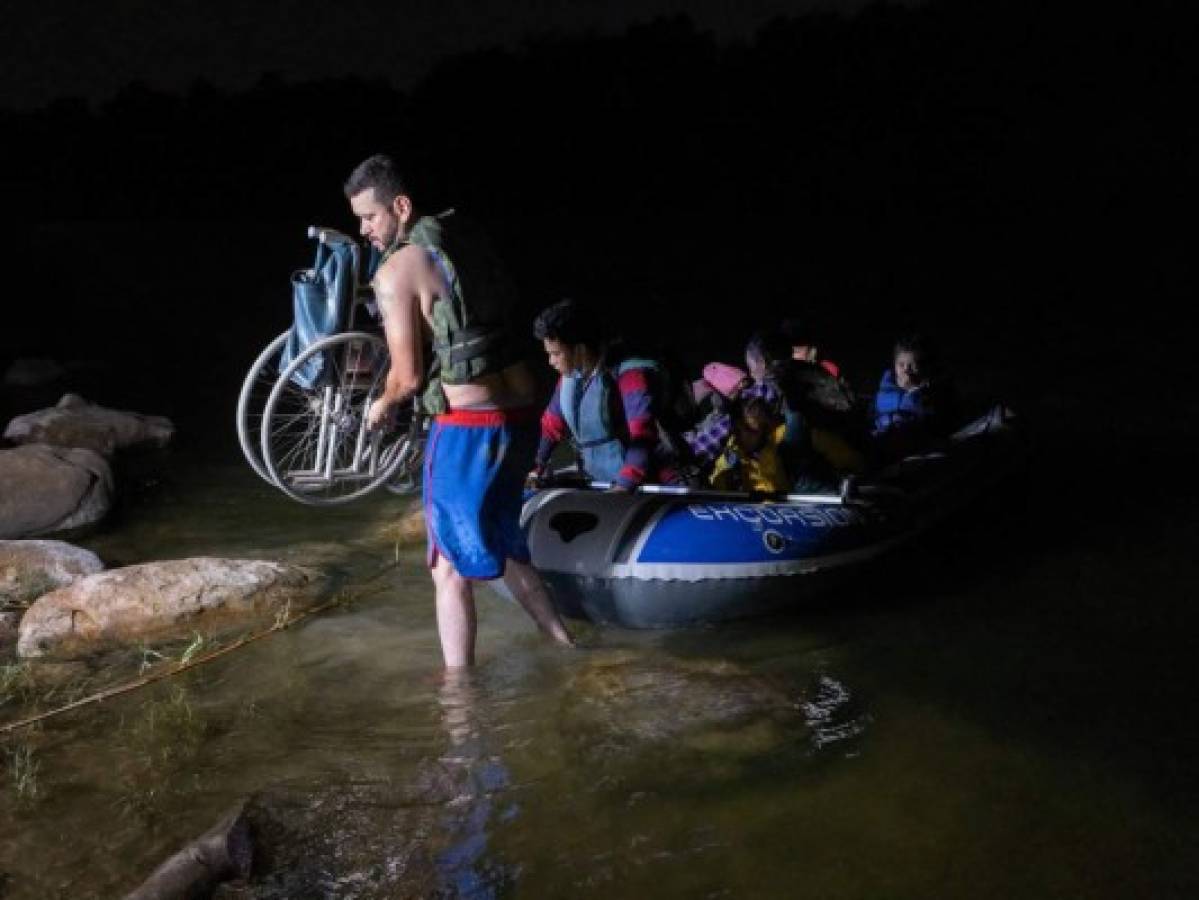 Un contrabandista carga la silla de ruedas de Tábora hacia la orilla del Río Grande.