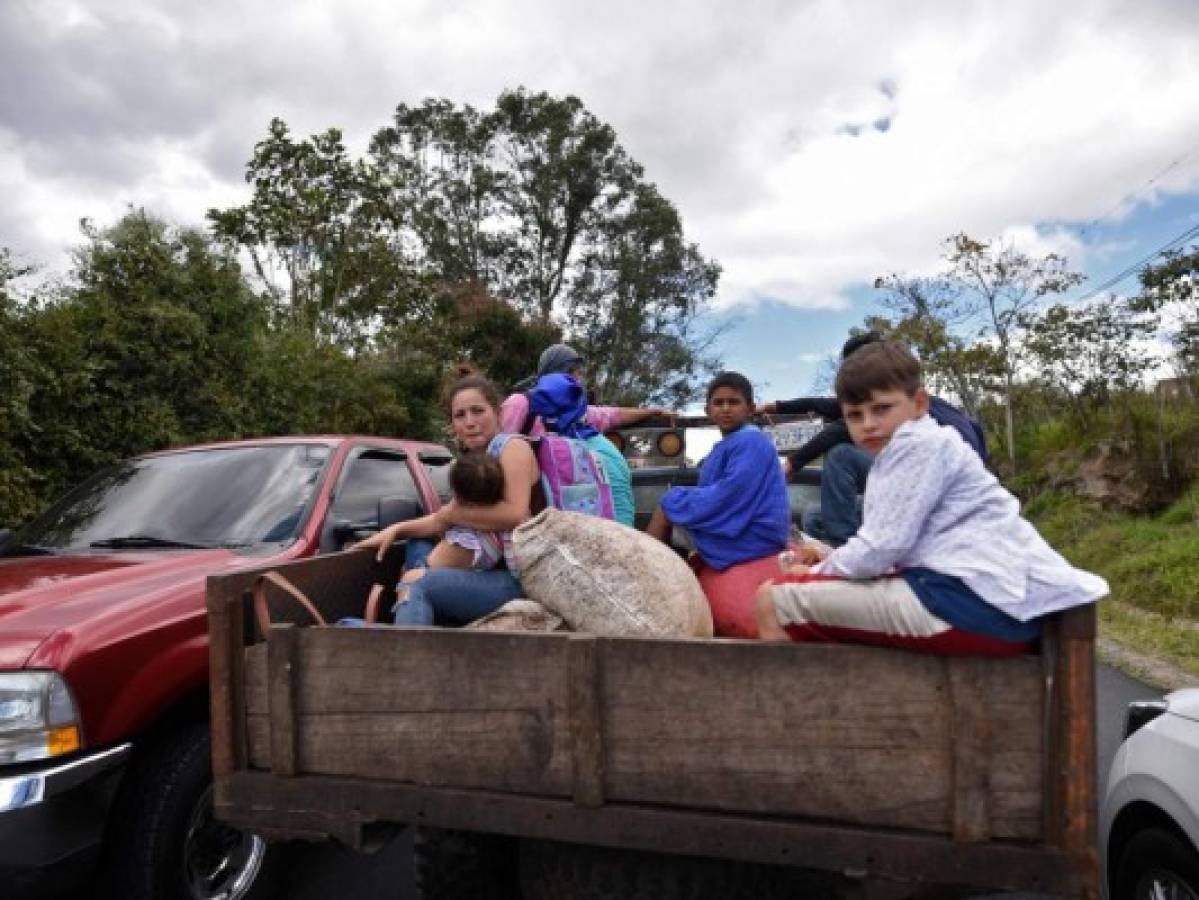 Una familia migrante viaja por la carretera en la paila de un vehículo que les dio jalón. Foto: Agencia AFP.