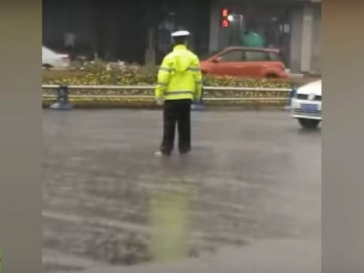 Policía regula el tráfico sin zapatos bajo fuerte lluvia en China