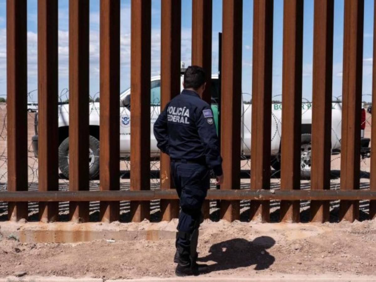 A Border patrol unit (behind the fence) and a Mexico's federal police guard near the US-Mexico border fence as US President Donald Trump visits Calexico, California, as seen from Mexicali, Baja California state, Mexico, on April 5, 2019. - President Donald Trump flew Friday to visit newly built fencing on the Mexican border, even as he retreated from a threat to shut the frontier over what he says is an out-of-control influx of migrants and drugs. (Photo by Guillermo Arias / AFP)