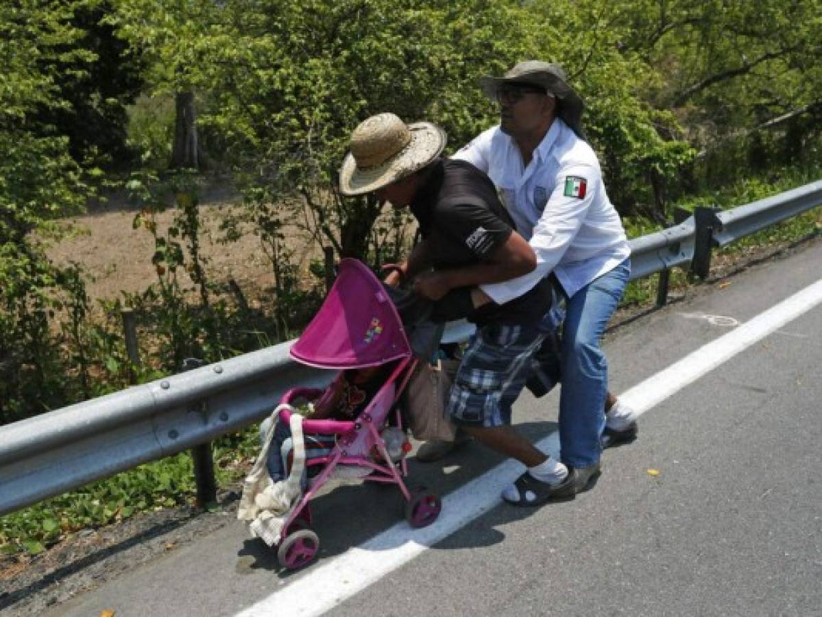 A Central American migrant pushing a child in a baby carriage is detained by a Mexican immigration agent from behind on the highway to Pijijiapan, Mexico, Monday, April 22, 2019. Mexican police and immigration agents detained hundreds of Central American migrants Monday in the largest single raid on a migrant caravan since the groups started moving through Mexico last year. (AP Photo/Moises Castillo)