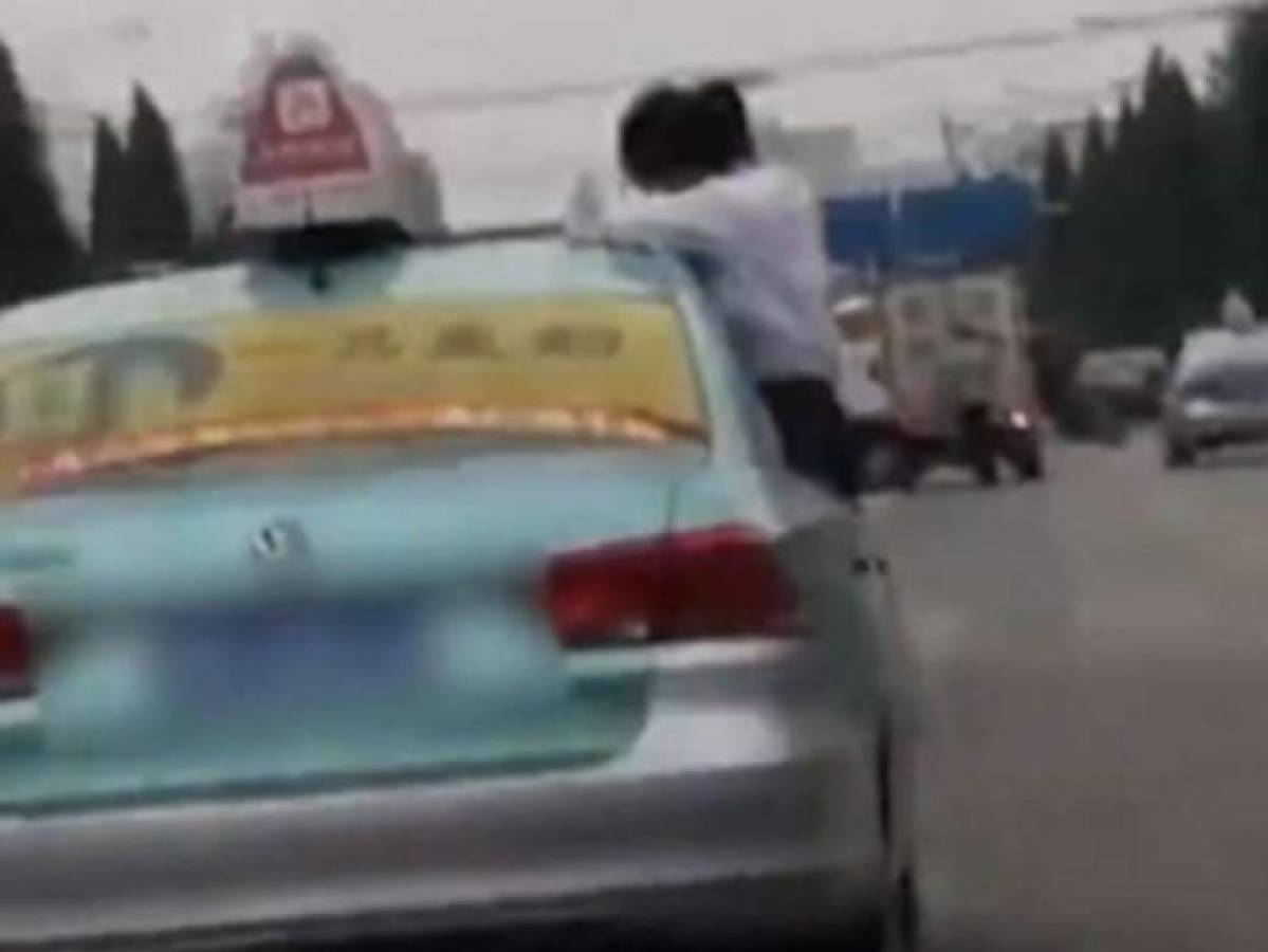 Beijin Time, publicó un vídeo en donde se observa a una estudiante china, terminando su tarea en el techo de un taxi en marcha. Foto: Captura de patalla del vídeo en Youtube