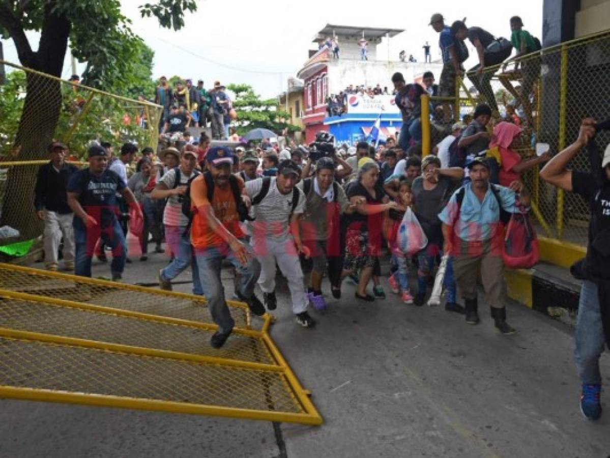 Los hondureños rompieron uno de los portones de la frontera Tecún Umán para poder cruzar la frontera. Foto AFP