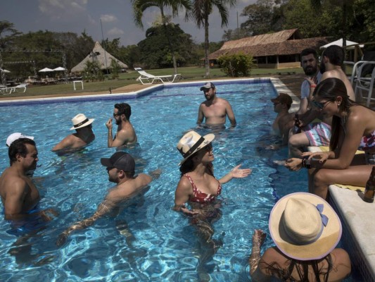 Los invitados a la boda campestre de María Fernanda Vera y Juan José Pocaterra disfrutan de la piscina en la hacienda Camburito de Acarigua, Venezuela, el 16 de febrero del 2019. (AP Photo/Rodrigo Abd).