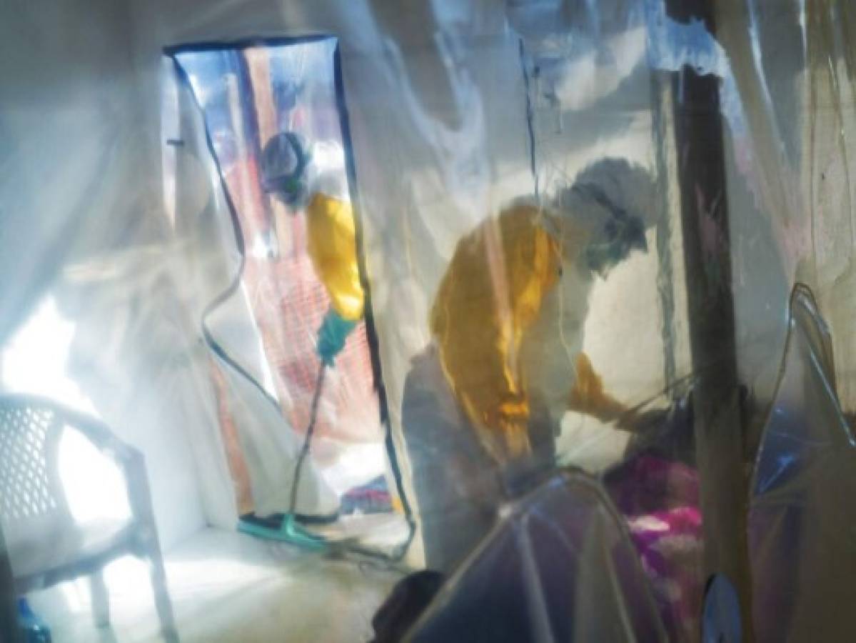 In this photograph taken Saturday 13 July 2019, health workers wearing protective suits tend to to an Ebola victim kept in an isolation cube in Beni, Congo DRC. The Congolese health ministry is confirming the country's first Ebola case in the provincial capital of 2 million, Goma, some 360 kms ( 225 miles) south of Beni. More than 1,600 people in eastern Congo have died as the virus has spread in areas too dangerous for health teams to access. (AP Photo/Jerome Delay)