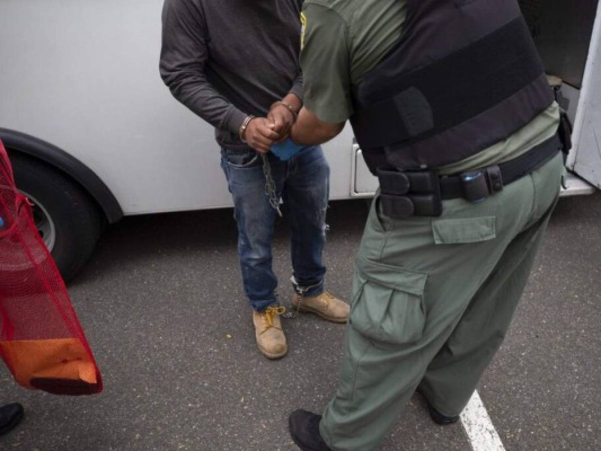 FILE - In this July 8, 2019, file photo, a U.S. Immigration and Customs Enforcement (ICE) officers transfer a man in handcuffs and ankle cuffs onto a van during an operation in Escondido, Calif. Advocacy groups and unions are pressuring Marriott, MGM and others not to house migrants who have been arrested by U.S. Immigration and Customs Enforcement agents. But the U.S. government says it sometimes needs bed space, and if hotels donât help it might have to split up families. (AP Photo/Gregory Bull, File)