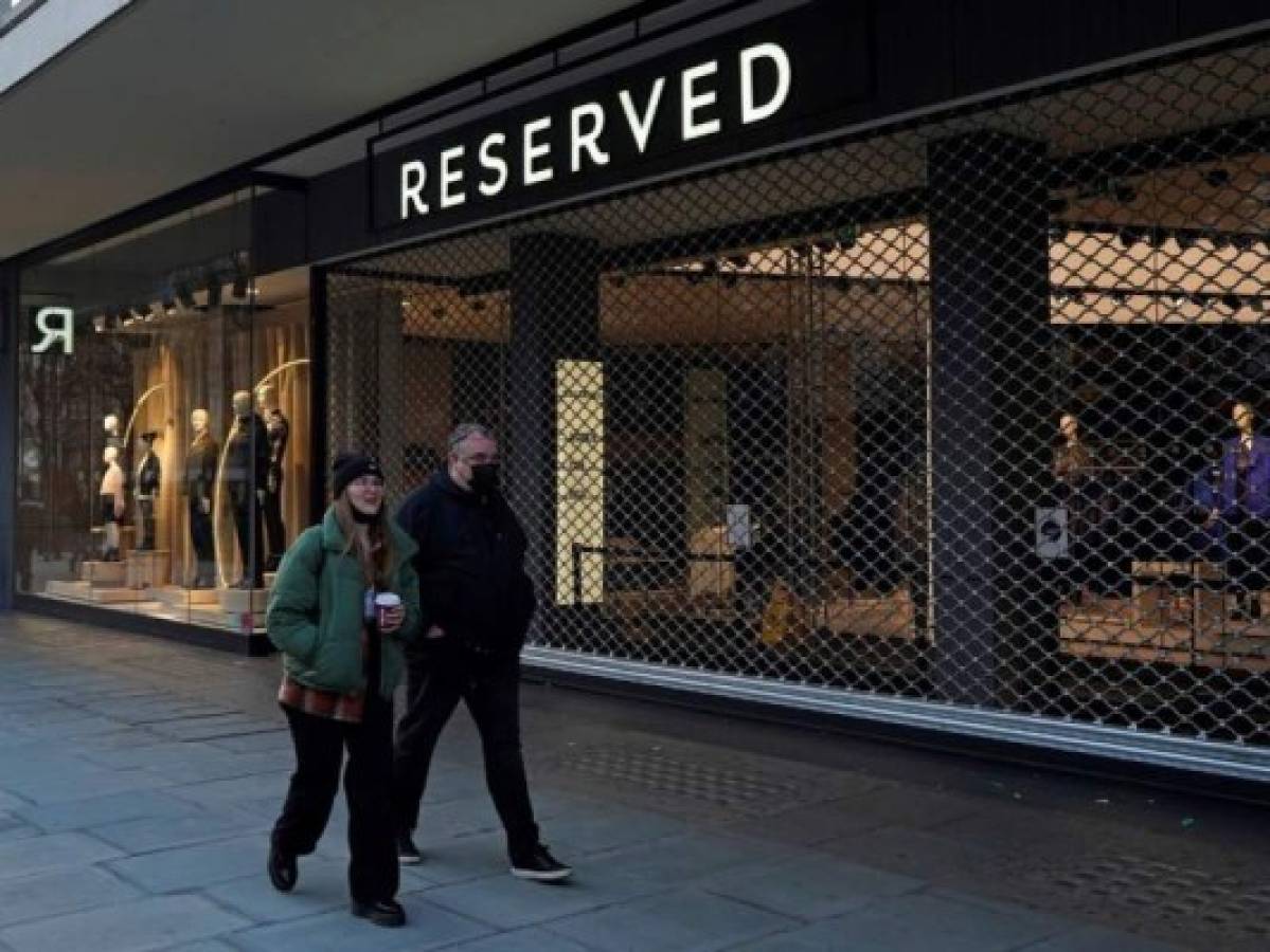 Los peatones que llevan una máscara facial o se cubren debido a la pandemia de covid-19, pasan por la entrada cerrada de una tienda, obligados a cerrar debido a las últimas restricciones de coronavirus de Nivel 4, en Oxford Street en el centro de Londres el 20 de diciembre de 2020.