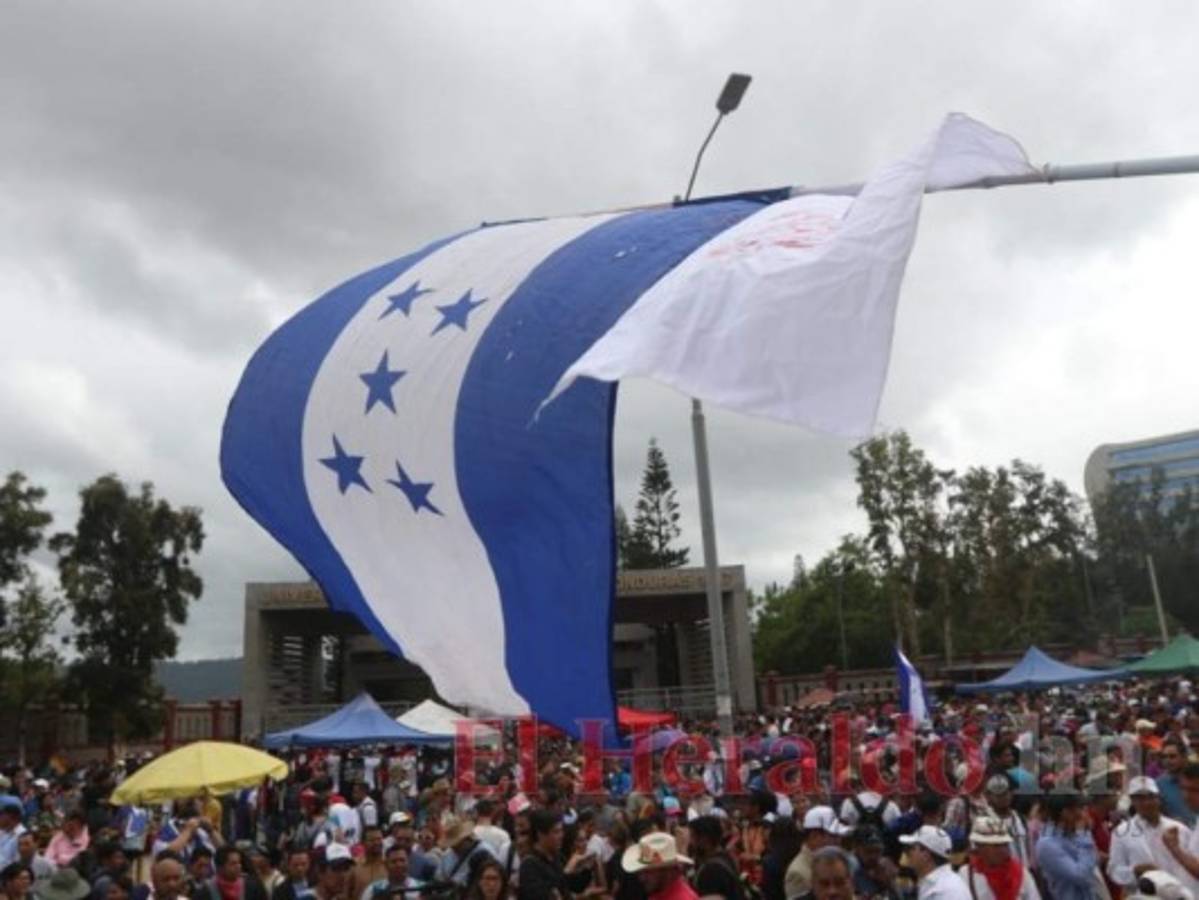 Con banderas en mano marchan estudiantes, maestros y miembros de la sociedad.