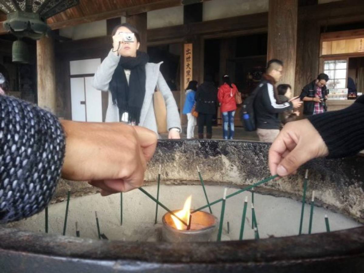 Visitantes queman incienso en la entrada de un templo, un rito común para purificación.
