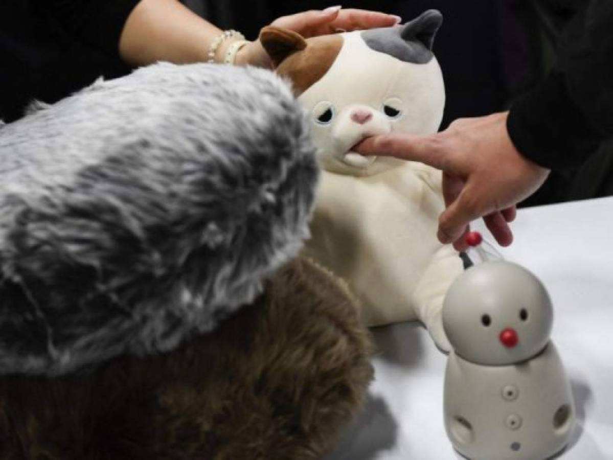 An attendee places a finger inside the mouth of Yukai Engineering Inc. Amagami Ham Ham play-biting cat robot, during CES Unveiled ahead of the Consumer Electronics Show (CES) on January 3, 2022 in Las Vegas, Nevada. - The Consumer Electronics Show (CES), one of the world's largest trade fairs, returns to Las Vegas in person this week under a newly resurgent pandemic that has supercharged the industry but threatens its downsized expo.Masks and proof of vaccination are required at the show that opens Wednesday and was trimmed by one day to end Friday, with expected exhibitors down more than half to roughly 2,200 from the last in-person CES. (Photo by Patrick T. FALLON / AFP)