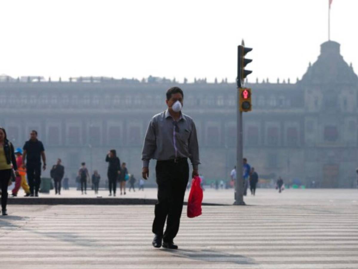 Algunos mexicanos usan mascarilla para no respirar el humo tóxico que envuelve la ciudad. FOTO: AP