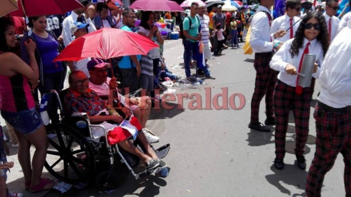 Con una sombrilla para soportar el fuerte sol, doña Ángela muestra su mejor sonrisa. Foto Yinely Suazo/EL HERALDO