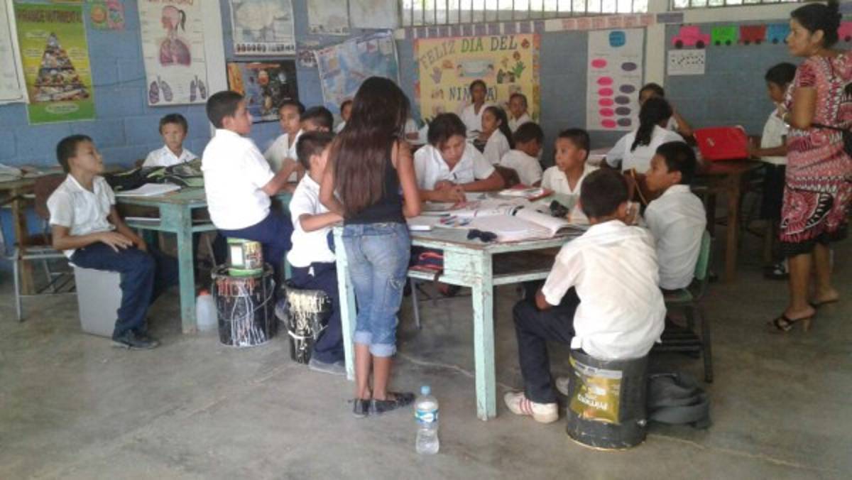 Varios niños se observan sentados sobre baldes plásticos. Aquí no existen condiciones pedagógicas para los alumnos.