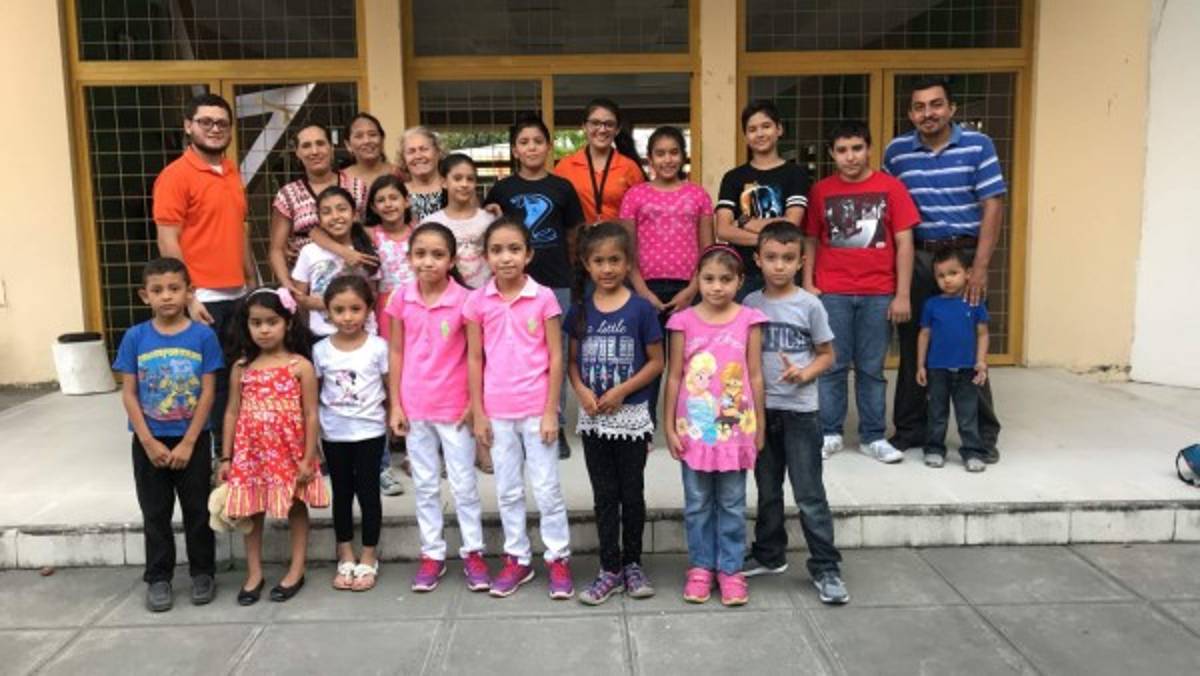 Los maestros Deuel Morales Rodríguez y Aura Mariela Platero -con camisetas color naranja- junto a padres de familia y alumnos de Choloma, Cortés.
