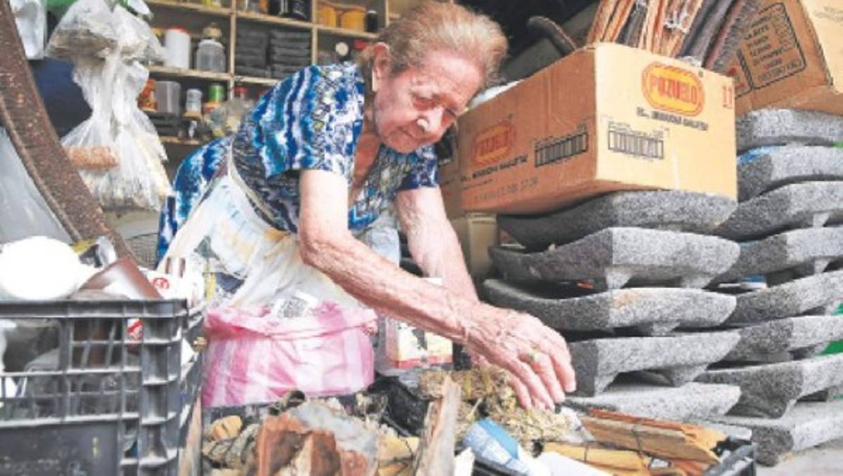 Emilia López en su puesto vende piedras para moler maíz, aceites, plantas aromáticas, entre otros productos curiosos.