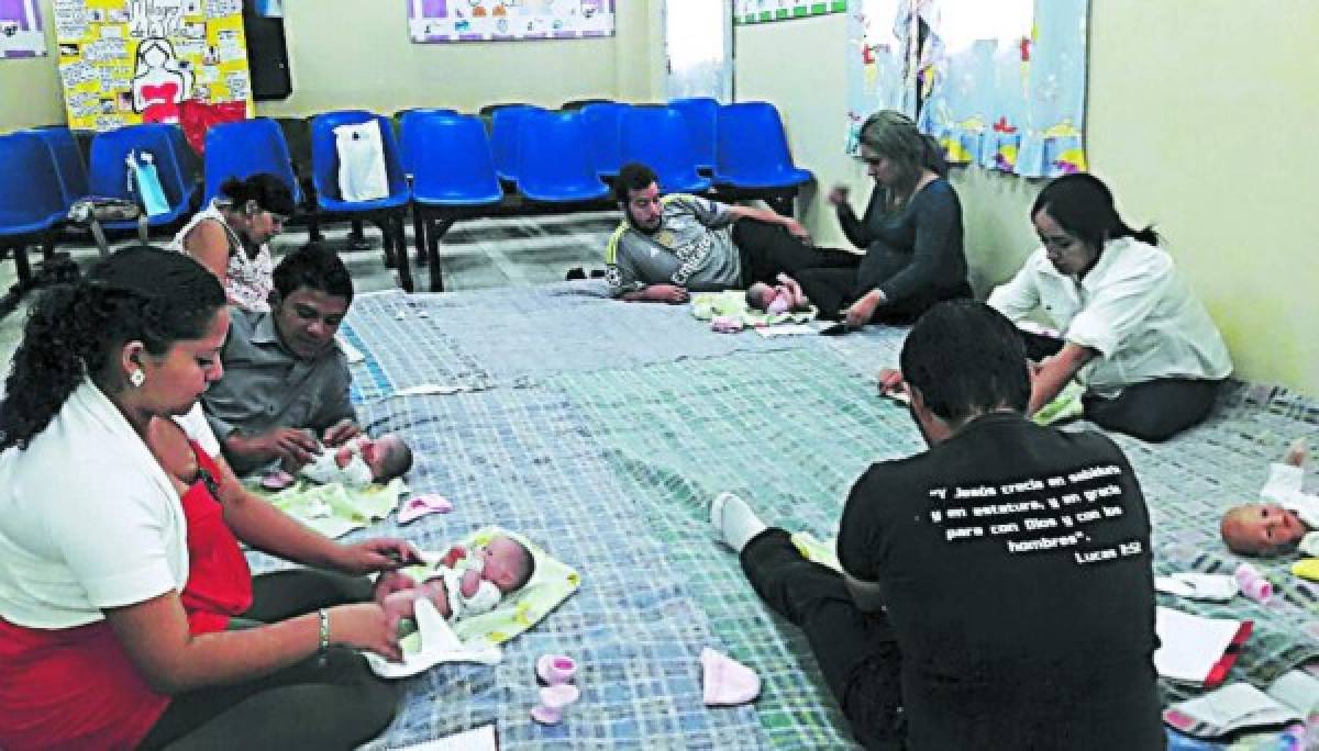 Las parejas aprenden con muñecos de plástico a cambiar a los bebés, a cargarlos, darles de comer y sacarles los gases.