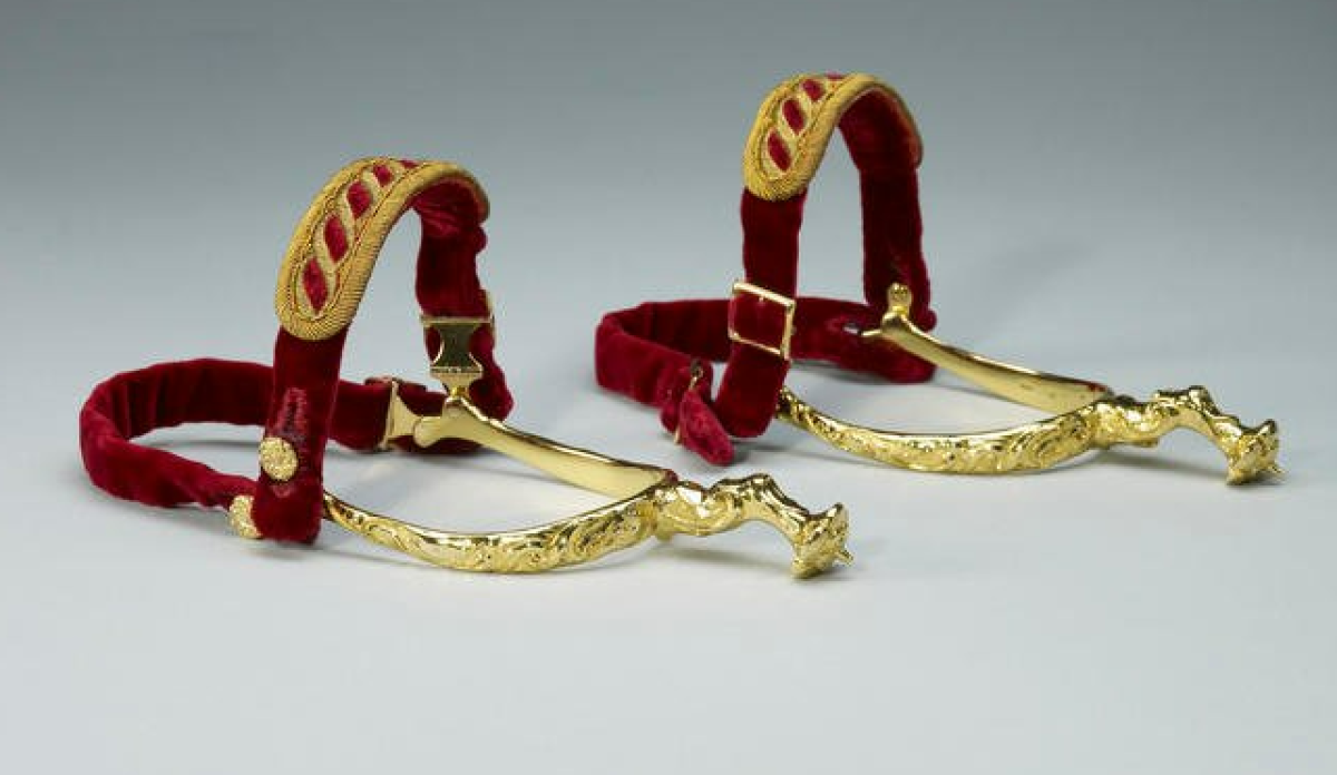 Tradicionalmente las espuelas se sujetaban a los pies del soberano, pero desde la Restauración simplemente se sujetan a los tobillos de los reyes.
