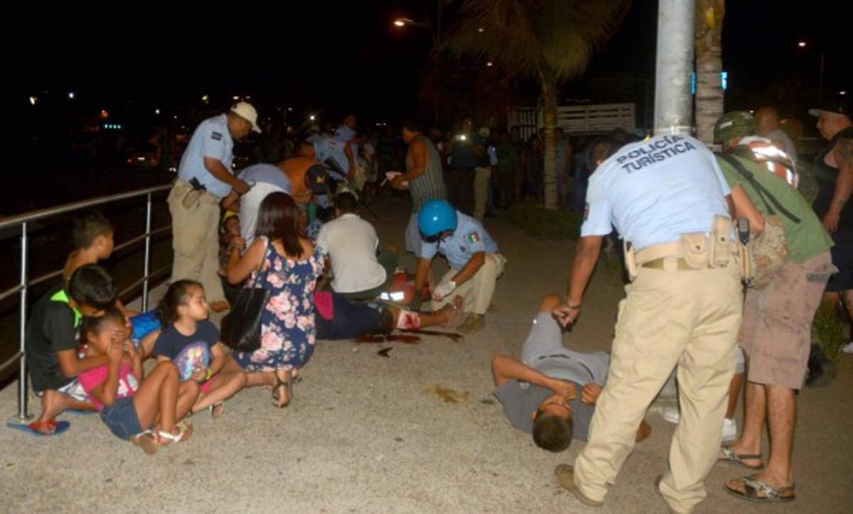 Members of Acapulco tourist police attend injured tourists after a shootout on April 15, 2017 in Acapulco, Mexico.A shootout in the tourist area of the resort left one dead and seven wounded on Saturday night, local authorities reported. / AFP PHOTO / FRANCISCO ROBLES