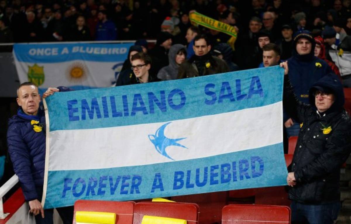 Fans hold up a banner in the colours of the Argentina flag honouring Cardiff's missing Argentinian player Emiliano Sala ahead of the English Premier League football match between Arsenal and Cardiff City at the Emirates Stadium in London on January 29, 2019. - A shipwreck hunter hired by the family of missing footballer Emiliano Sala to look for his missing plane said he was planning to begin an underwater search on Sunday. David Mearns of Bluewater Recoveries said on Monday, January 28, 2019, that two fishing boats were searching the sea around the island of Guernsey as part of the search. (Photo by Ian KINGTON / AFP) / RESTRICTED TO EDITORIAL USE. No use with unauthorized audio, video, data, fixture lists, club/league logos or 'live' services. Online in-match use limited to 120 images. An additional 40 images may be used in extra time. No video emulation. Social media in-match use limited to 120 images. An additional 40 images may be used in extra time. No use in betting publications, games or single club/league/player publications. /