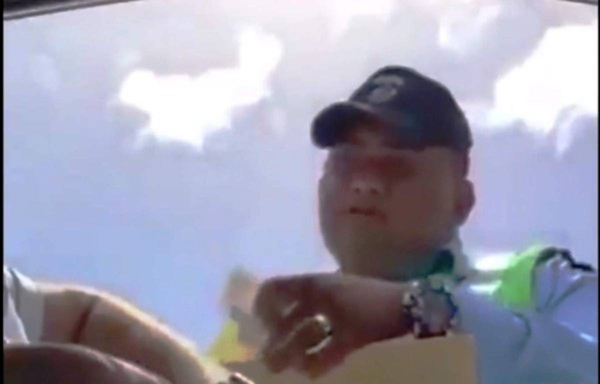 El agente de tránsito le pide al conductor del vehículo que le pase el dinero abajo de la licencia.