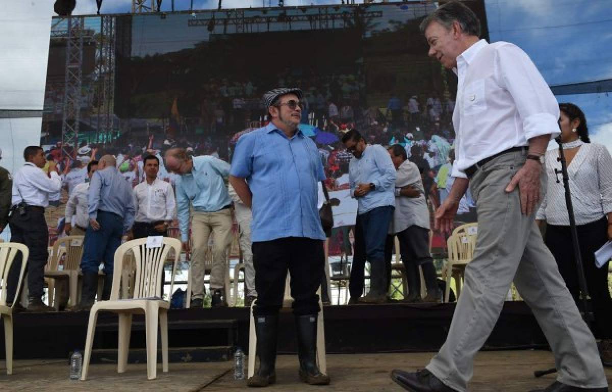 FARC rebel leader Rodrigo Londono Echeverri, known as 'Timochenko'(L) and Colombian President Juan Manuel Santos (R) attend the final act of abandonment of arms and FARC's end as an armed group at Transitional Standardization Zone Mariana Paez, Buena Vista, Mesetas municipality, Colombia on June 27, 2017. / AFP PHOTO / RAUL ARBOLEDA