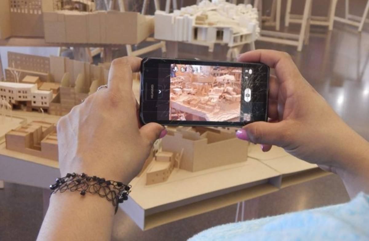 En la Biblioteca Jaume Fuster se detiene para tomarles fotos a unas maquetas de arquitectura y enviarlas a su hermano en Honduras.