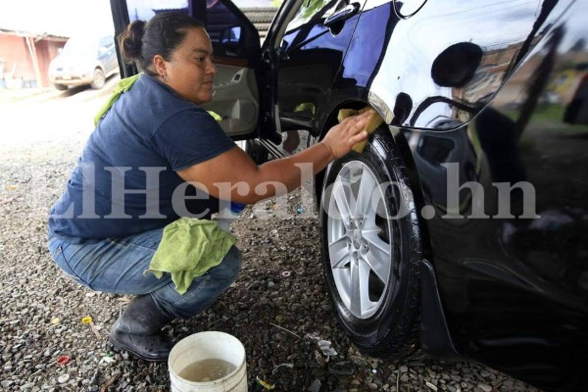 Ligia limpia las llantas de los vehículos con empeño y entusiasmo. Foto Marvin Salgado