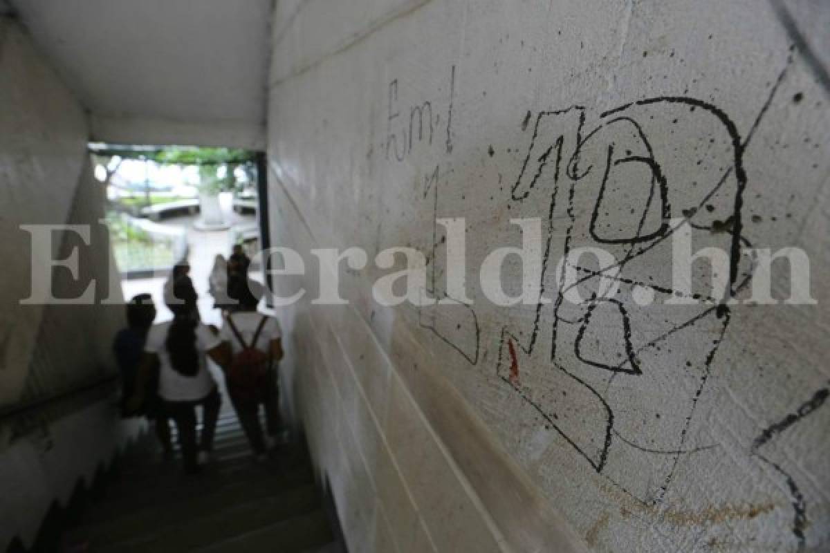 Alumnas pasan frente a un grafiti dentro del colegio.