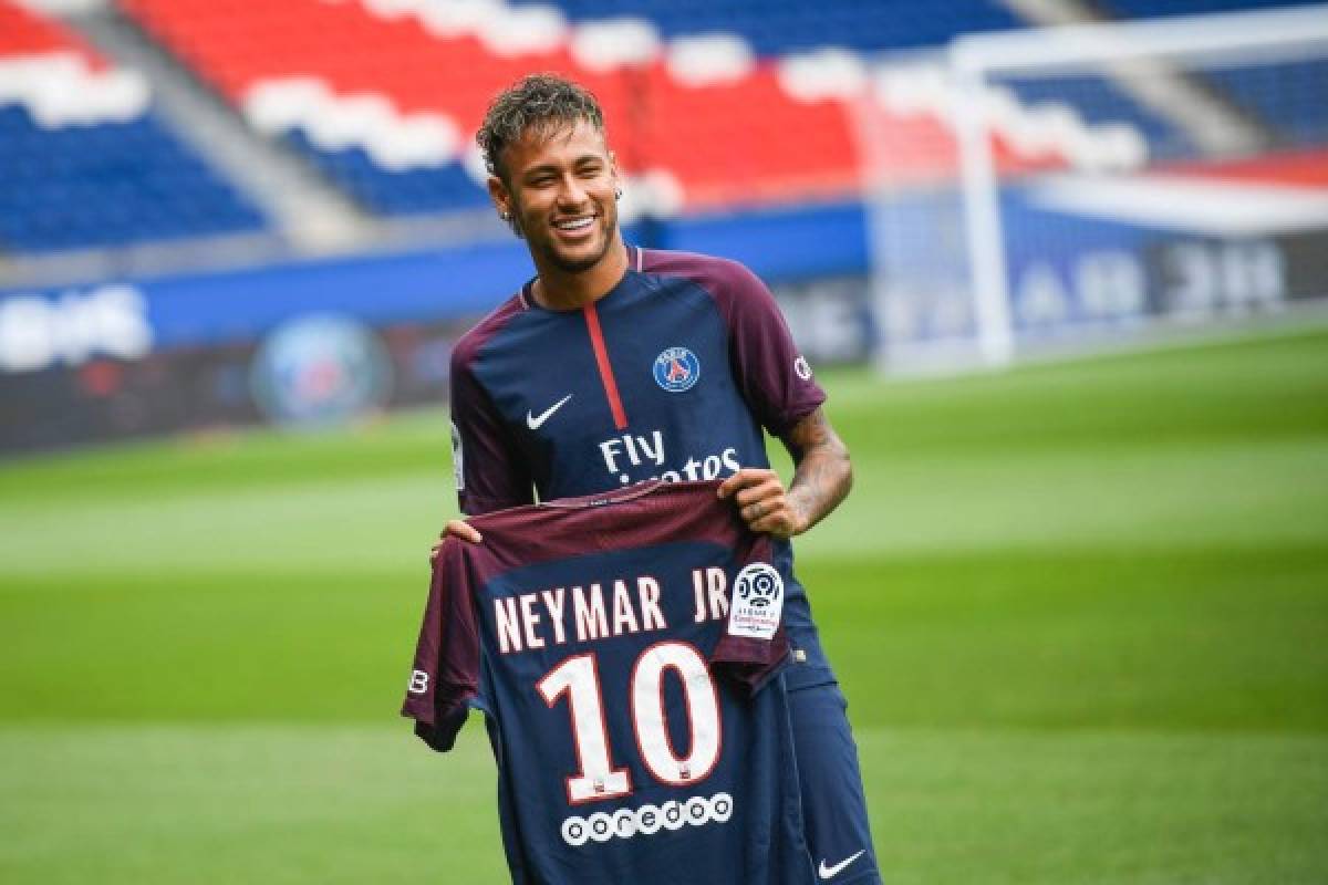 TOPSHOT - Brazilian superstar Neymar poses with his new jersey during his official presentation at the Parc des Princes stadium on August 4, 2017 in Paris after agreeing a five-year contract following his world record 222 million euro ($260 million) transfer from Barcelona to Paris Saint Germain's (PSG).Paris Saint-Germain have signed Brazilian forward Neymar from Barcelona for a world-record transfer fee of 222 million euros (around $264 million), more than doubling the previous record. Neymar said he came to Paris Saint-Germain for a 'bigger challenge' in his first public comments since arriving in the French capital. / AFP PHOTO / Lionel BONAVENTURE