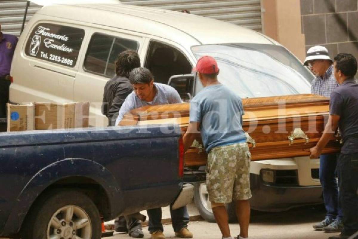 Dos hombres ayuda a subir el féretro a un carro para llevarlo a su casa. Foto: Estalin Irias/El Heraldo.