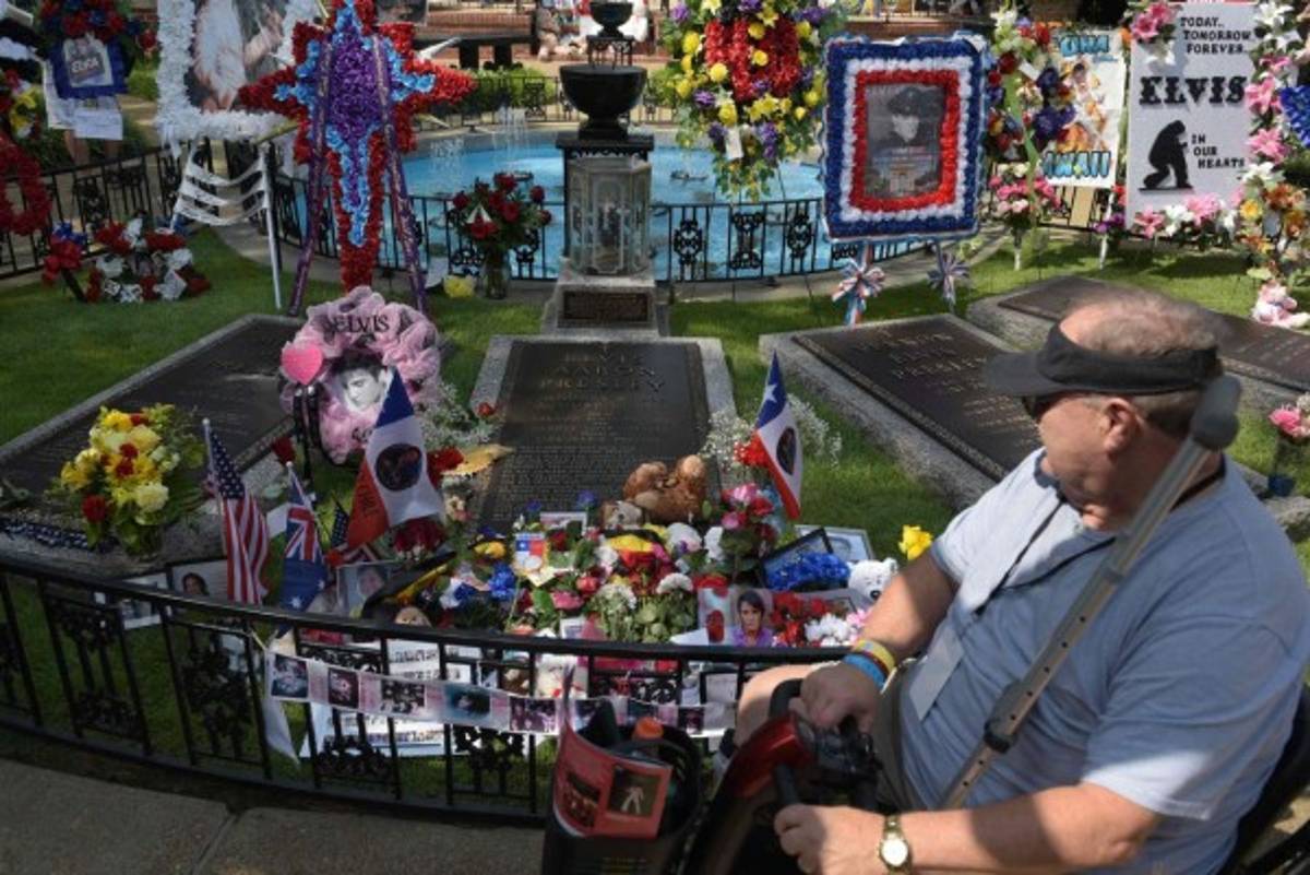 Fans file past the grave of Elvis Presley in the Meditation Garden where he is buried alongside his parents and grandmother at his Graceland mansion on August 12, 2017 in Memphis, Tennessee.Elvis Presley, American icon and King of rock n roll, transformed popular culture, sold over a billion records and is idolized as ever on the 40th anniversary of his tragic death.His Graceland mansion in Memphis, Tennessee -- the second most famous home in the United States after the White House -- expects more than 50,000 people to descend for the biggest ever annual celebration of his life 40 years after his death aged 42 on August 16, 1977. / AFP PHOTO / MANDEL NGAN / With AFP Story by Jennie MATTHEW: Elvis: 40 years since the death of an American icon