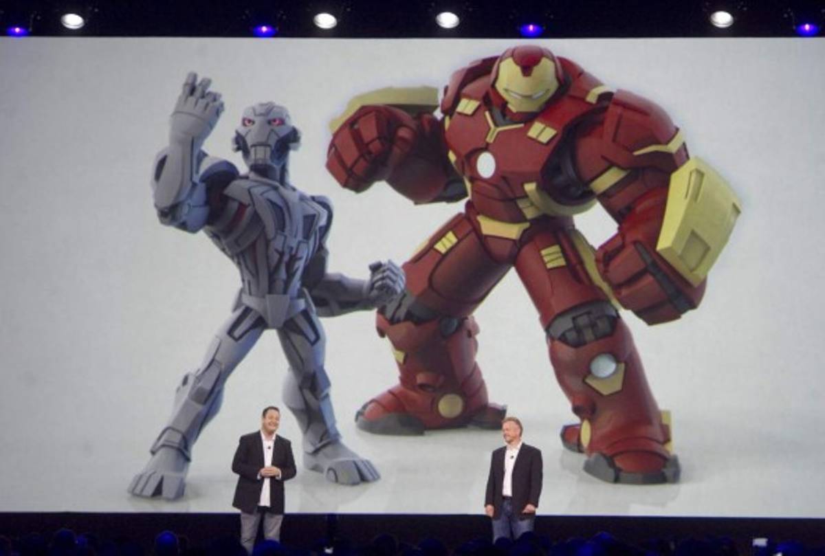 In this Sunday, Aug. 16, 2015, photo, Ironman characters appear larger than life at the D23 Expo where John Vignocchi, at left, and John Blackburn talk about Battlegrounds, a new name for the Marvel playset for Disney Infiniaty 3.0, in Anaheim, Calif. (Mindy Schauer/The Orange County Register via AP)