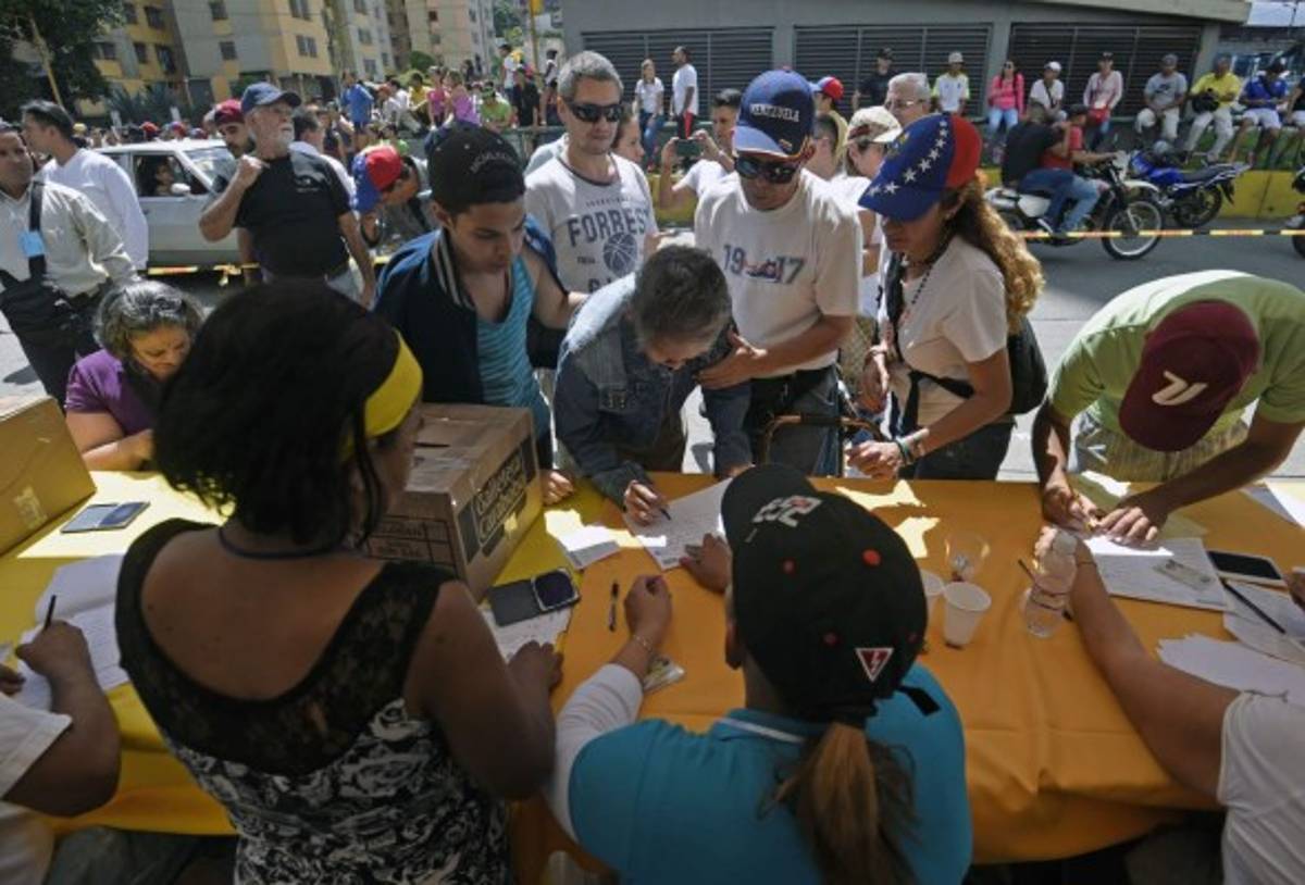 People cast their votes at a polling station in Caracas on July 16, 2017 during an opposition-organized vote to measure public support for Venezuelan President Nicolas Maduro's plan to rewrite the constitution.Authorities have refused to greenlight the vote that has been presented as an act of civil disobedience and supporters of Maduro are boycotting it. Protests against Maduro since April 1 have brought thousands to the streets demanding elections, but has also left 96 people dead, according to an official toll. / AFP PHOTO / JUAN BARRETO