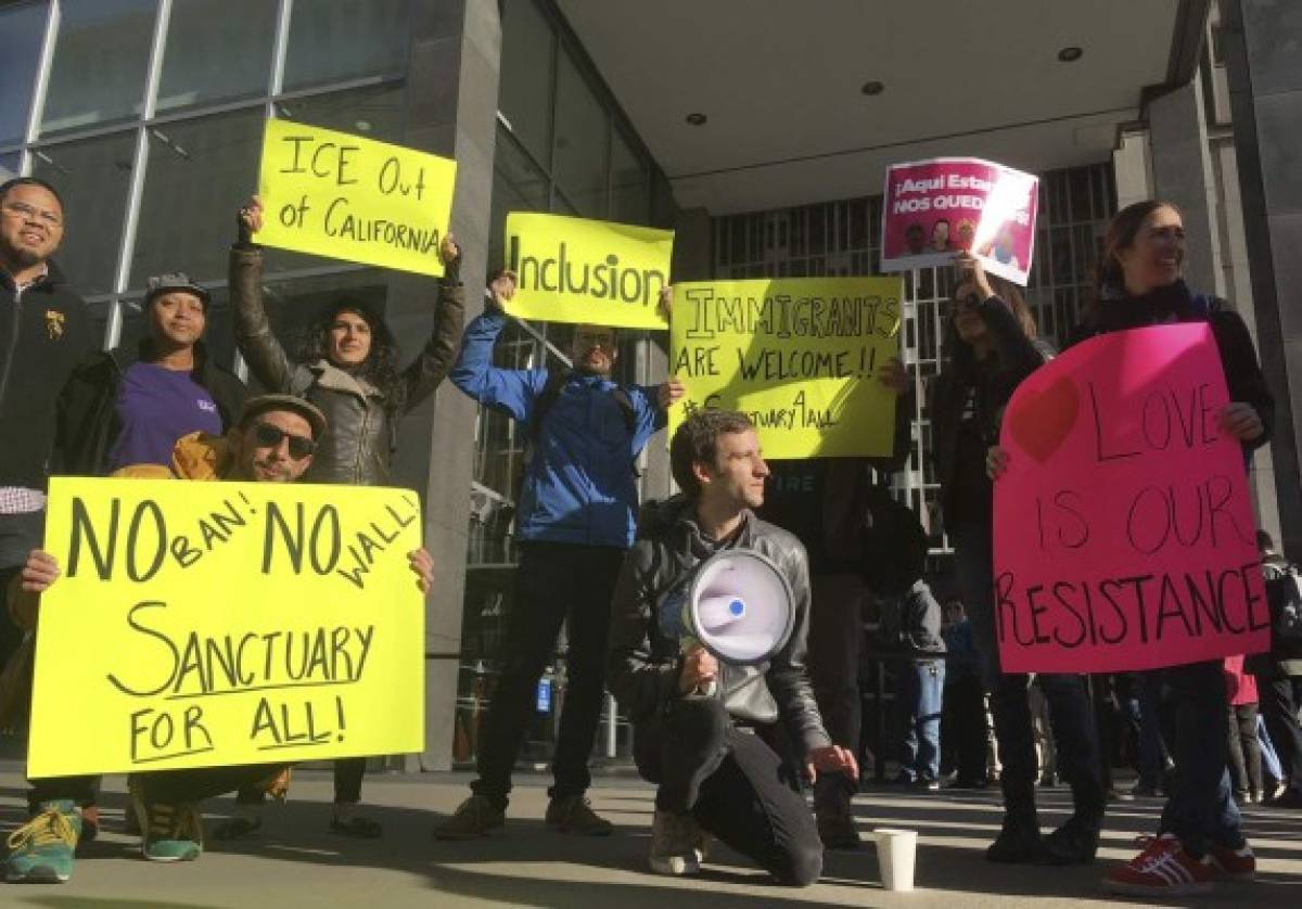 Protesters hold up signs outside a courthouse where a federal judge will hear arguments in the first lawsuit challenging President Donald Trump's executive order to withhold funding from communities that limit cooperation with immigration authorities Friday, April 14, 2017, in San Francisco. U.S. District Court Judge William Orrick has scheduled a hearing on Friday on San Francisco's request for a court order blocking the Trump administration from cutting off funds to any of the nation's so-called sanctuary cities. (AP Photo/Haven Daley)
