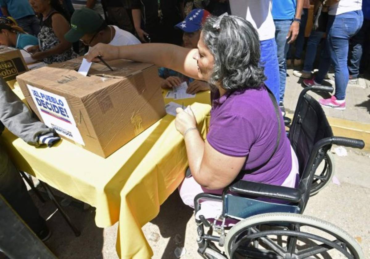 A woman casts her vote at a polling station in Caracas on July 16, 2017 during an opposition-organized vote to measure public support for Venezuelan President Nicolas Maduro's plan to rewrite the constitution.Authorities have refused to greenlight the vote that has been presented as an act of civil disobedience and supporters of Maduro are boycotting it. Protests against Maduro since April 1 have brought thousands to the streets demanding elections, but has also left 96 people dead, according to an official toll. / AFP PHOTO / JUAN BARRETO