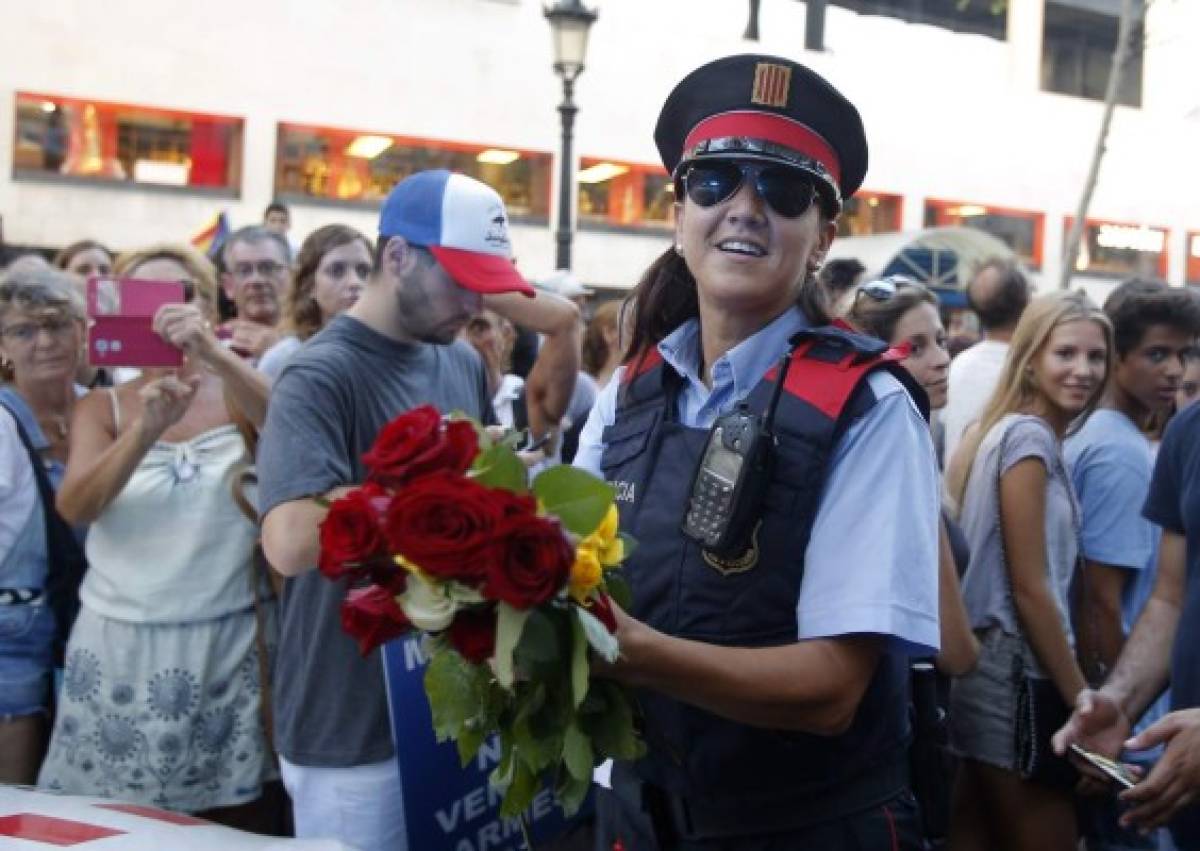 Una mujer policía sostiene flores ofrecidas por personas al final de una manifestación que condena los ataques que mataron a 15 personas la semana pasada en Barcelona, España. (Foto: AFP/ El Heraldo Honduras/ Noticias de Honduras)